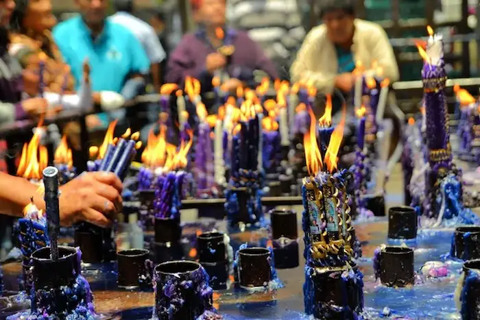 Personas velando con velas moradas en honor a la Festividad del Señor de los Milagros