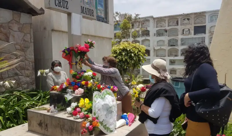 Señoras coronando a sus difuntos en el cementerio como parte de la celebración por el día de todos los santos