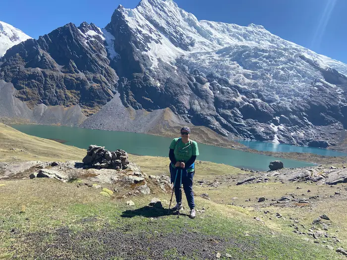 Mujer en medio de un paisaje despampanante en medio de las montañas mientras realiza un trekking en peru