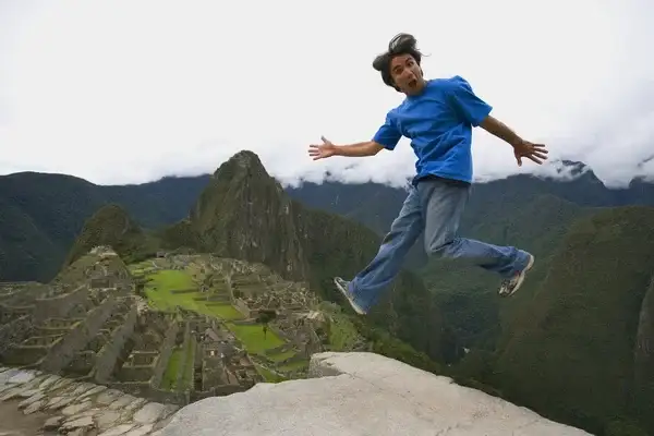 Turista saltando sobre Machu Picchu